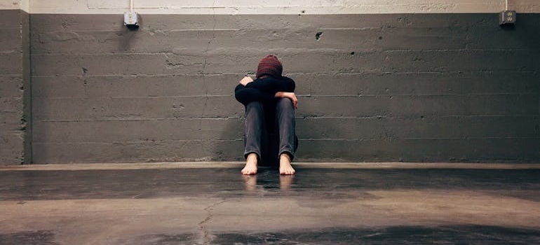 Person sitting on the floor, hugging their knees while struggling with depression.