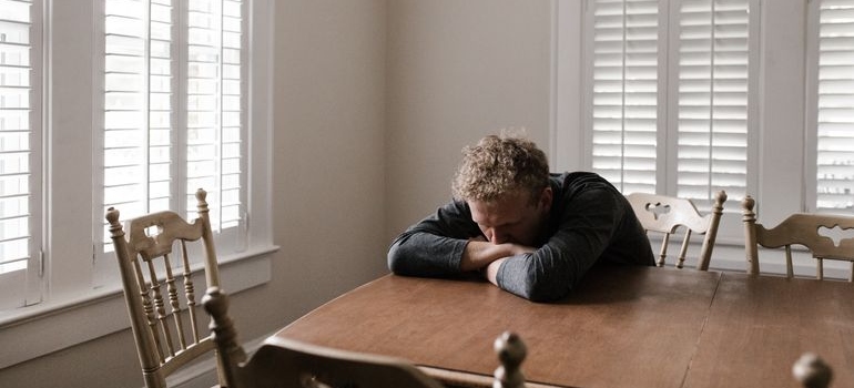 Man leaning on the table and worrying about effects of alcohol on the brain.