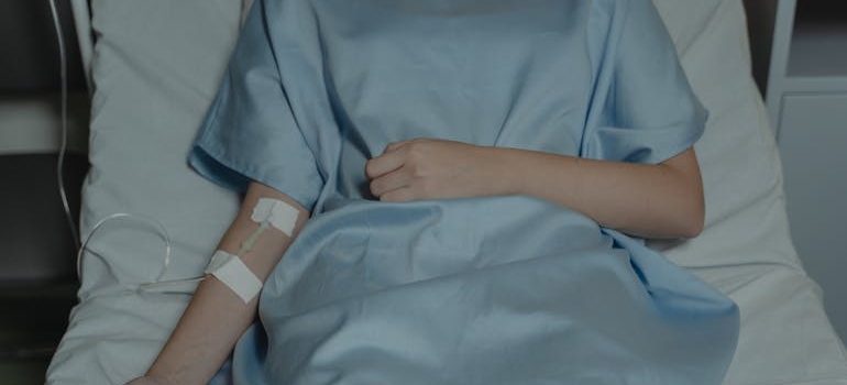 Woman lying in a hospital bed receiving an IV.
