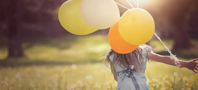 A girl holding yellow balloons.