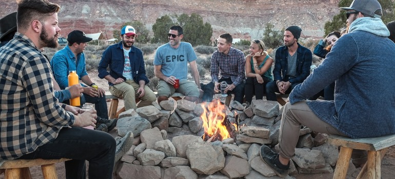 A group of men sitting next to a fire pit.