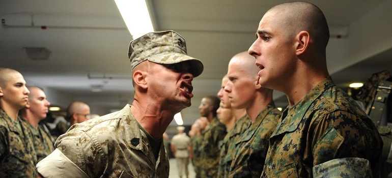 Drill sergeant yelling at soldier.