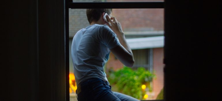A man sitting on a window sill.