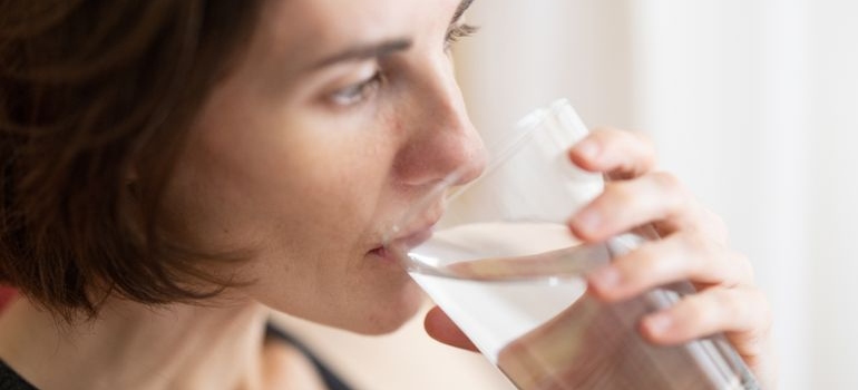 Woman drinking a glass of water during a calm morning routine.