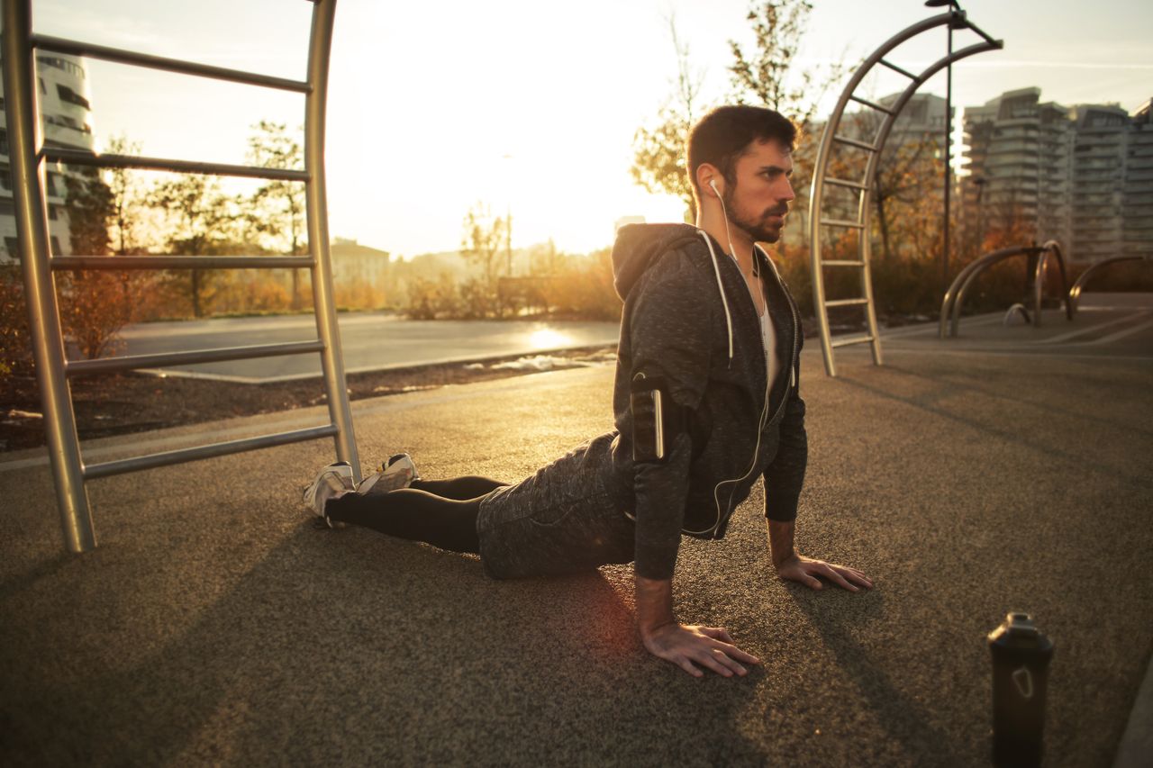 Man practicing yoga outdoors at sunrise as part of a healthy routine.
