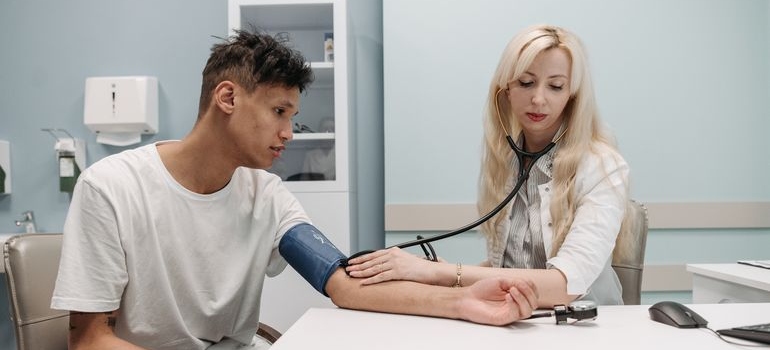 Doctor checking a man’s blood pressure while discussing changes you can expect after you stop drinking.