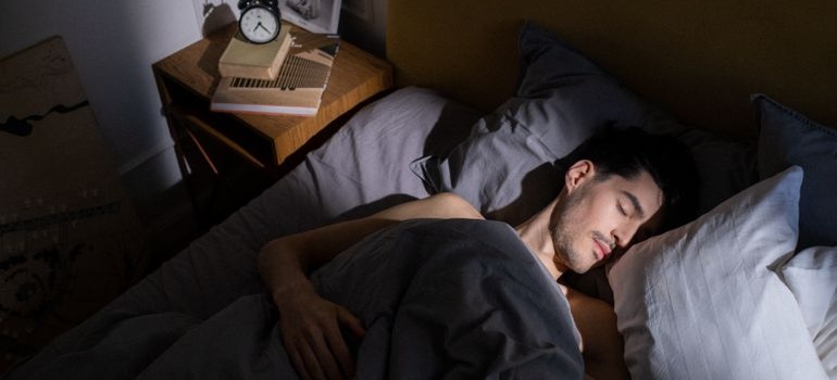 Man sleeping peacefully in bed with morning sunlight.
