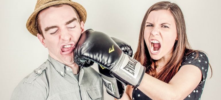 A woman punching a guy with a boxing glove.