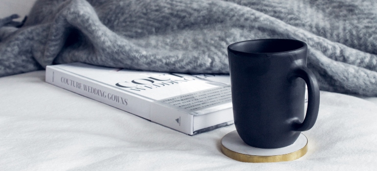 a mug and a book beneath a blanket