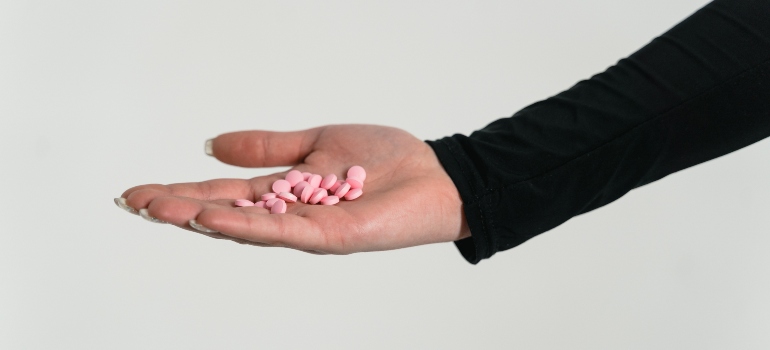 person holding pink pills in their palm