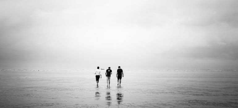 Three people walking down the beach.