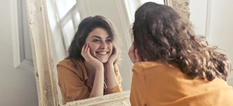 a happy woman smiling in the mirror 