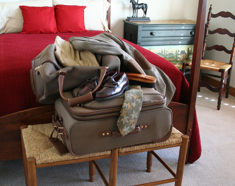 Luggage on chairs by a bed.