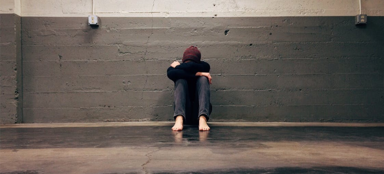 A depressed individual leaning on a wall.