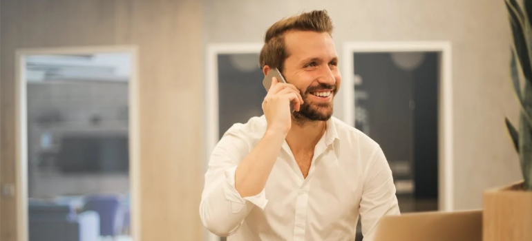 A smiling man talking on a mobile phone.
