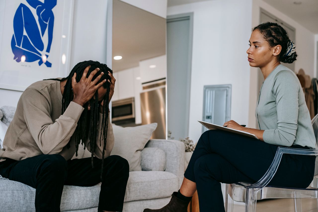 Young man receiving emotional support from a therapist during a private counseling session.