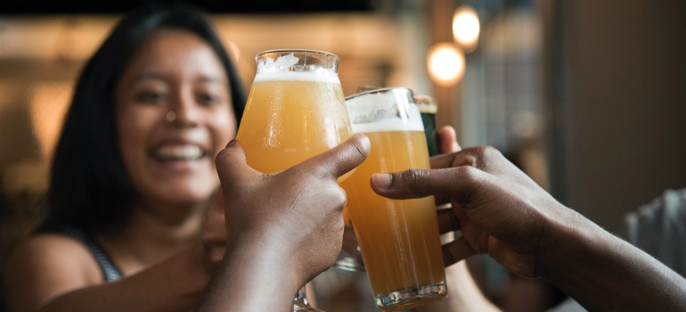 people clinking beer glasses at a bar without thinking whether is non-alcoholic beer safe for recovering alcoholics
