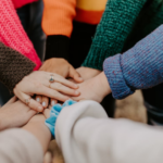 A close-up of friends joining hands, illustrating peer support in addiction treatment.