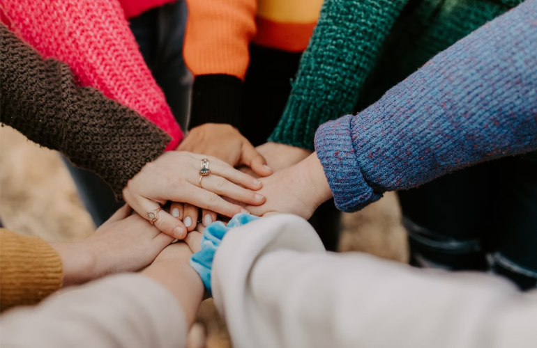 A close-up of friends joining hands, illustrating peer support in addiction treatment.