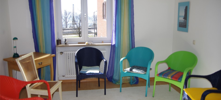 Chairs in different colors in a room, symbolizing group therapy and peer support in addiction treatment