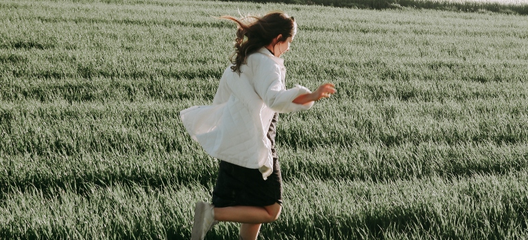 person running in a grass field as a part of one of the holistic therapies for Pennsylvania addiction recovery