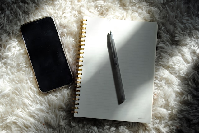 A notepad, a pen, and a phone for journaling.