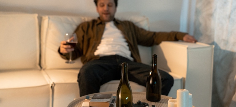 Person sitting on a couch and watching tv with empty beer bottles in front of them