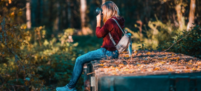 Woman taking a photo in the forest as an example of revisiting an old hobby which is one of the lesser- known benefits of addiction recovery