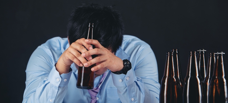 a sad man holding an alcoholic drink, representing Hangziety