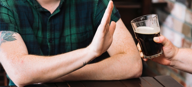 person refusing a glass of alcohol, representing Educating the Spouse for Successful Recovery