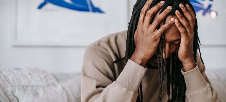 Man experiencing hangxiety and physical discomfort at home.