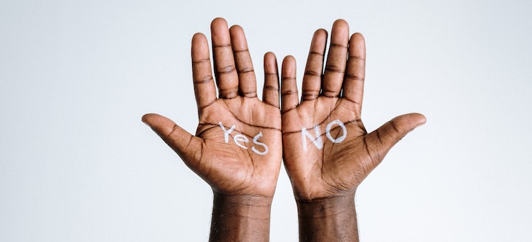 A person's hands with yes and no written on them