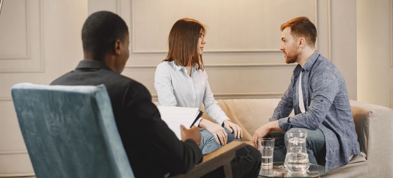 Couple talking with a therapist and looking at each other.
