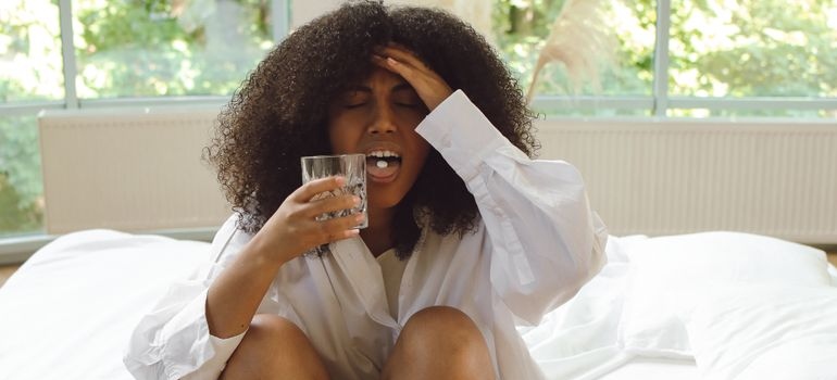 Woman with hangxiety holding water during a hangover.
