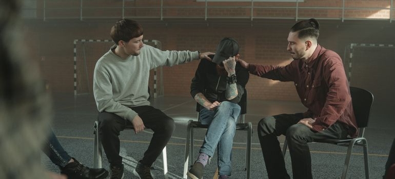 Two men comforting a friend in a support group meeting.
