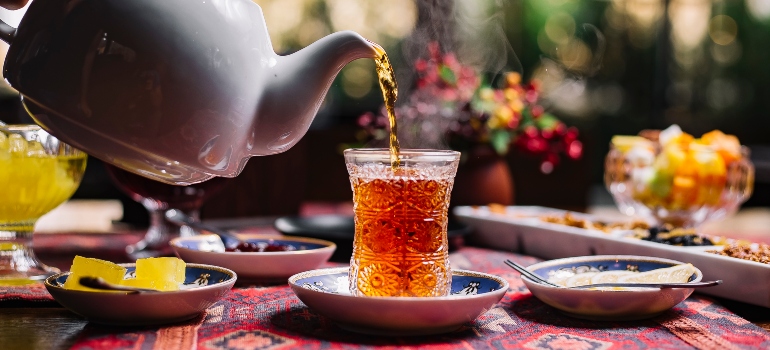 A cup of herbal tea being poured against a natural background