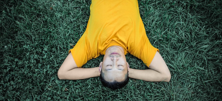 a person in yellow tshirt lying on grass