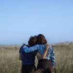 Two friends hugging in a field.