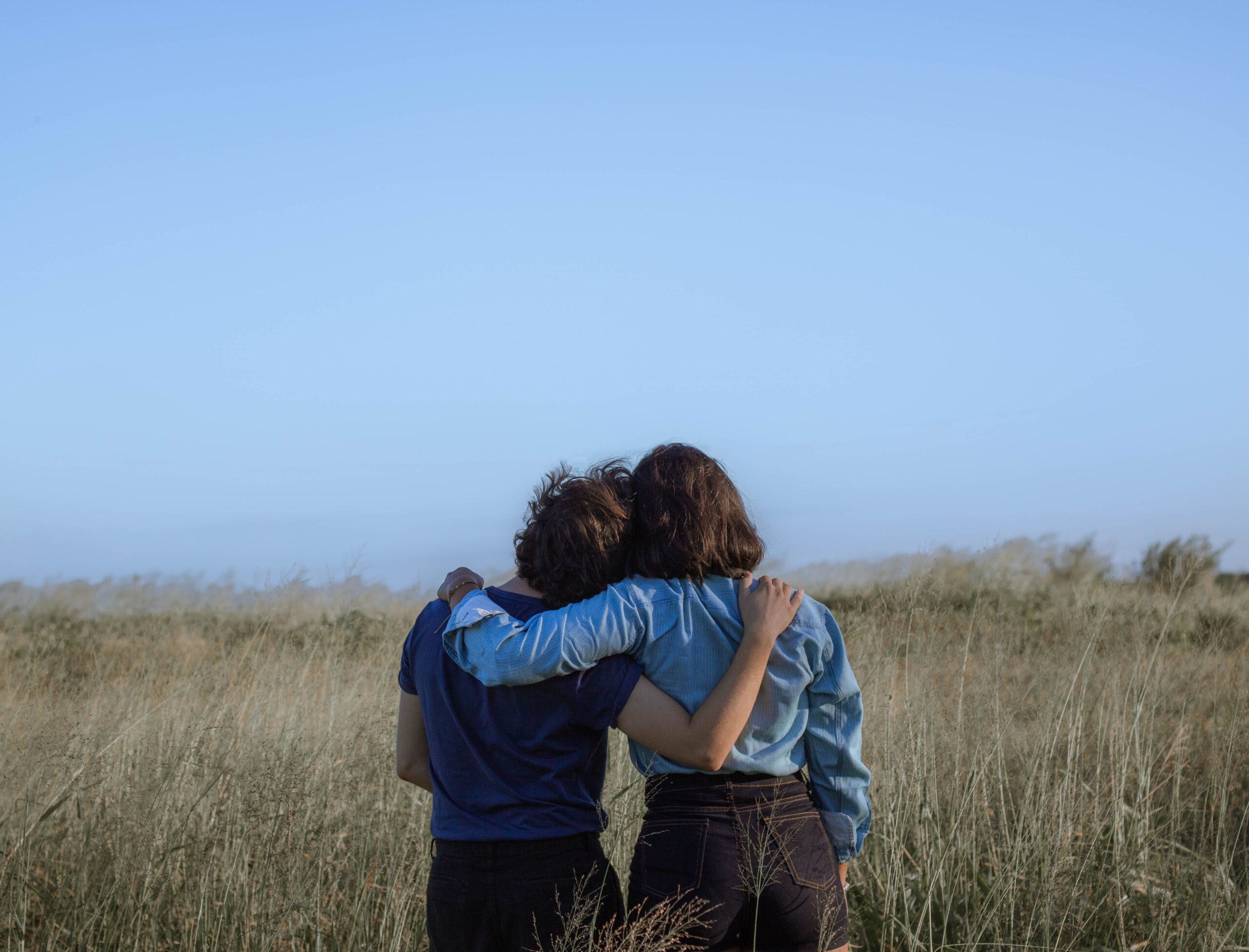 Two friends hugging in a field.
