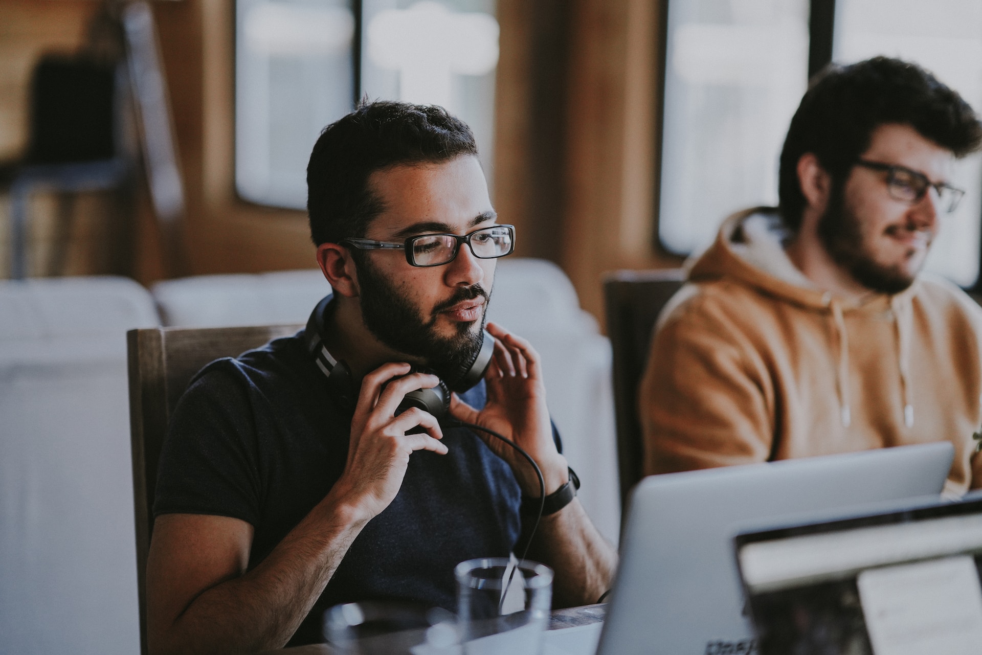 A man wearing glasses and headphones near a colleague representing how to handle a coworker's drug or alcohol addiction