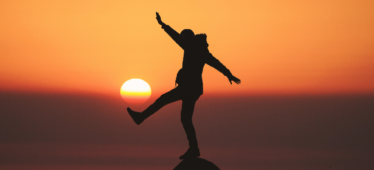 a silhouette of a man balancing in front of the sun