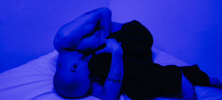 a man laying on a bed feeling blue, while the photo is blue
