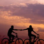 a woman and a men ridding a bike at sunset