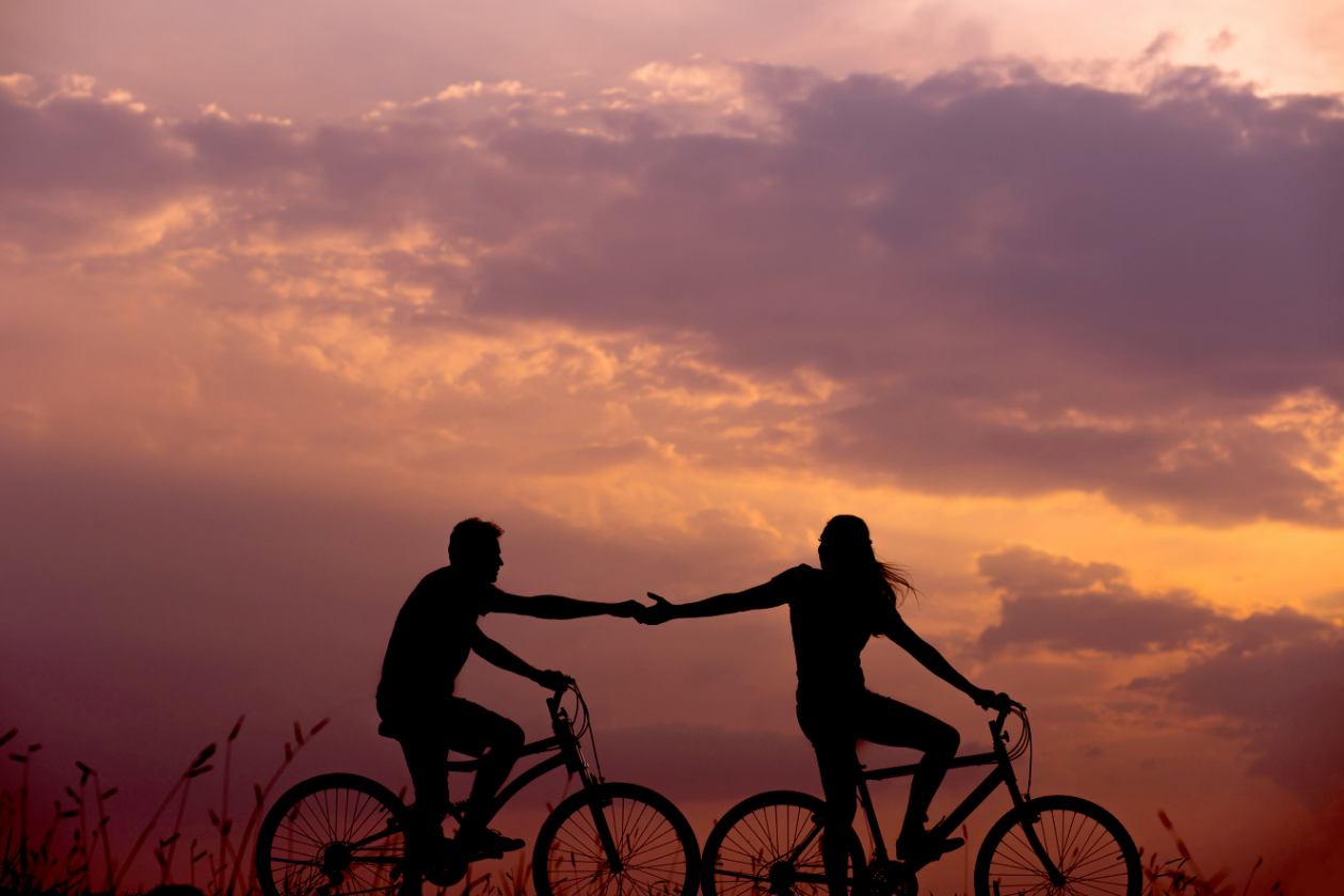 a woman and a men ridding a bike at sunset