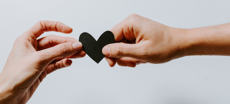 two hands holding a black paper heart as a part of the role of partners in men's recovery journey