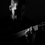 man making music in recovery on guitar in dim light