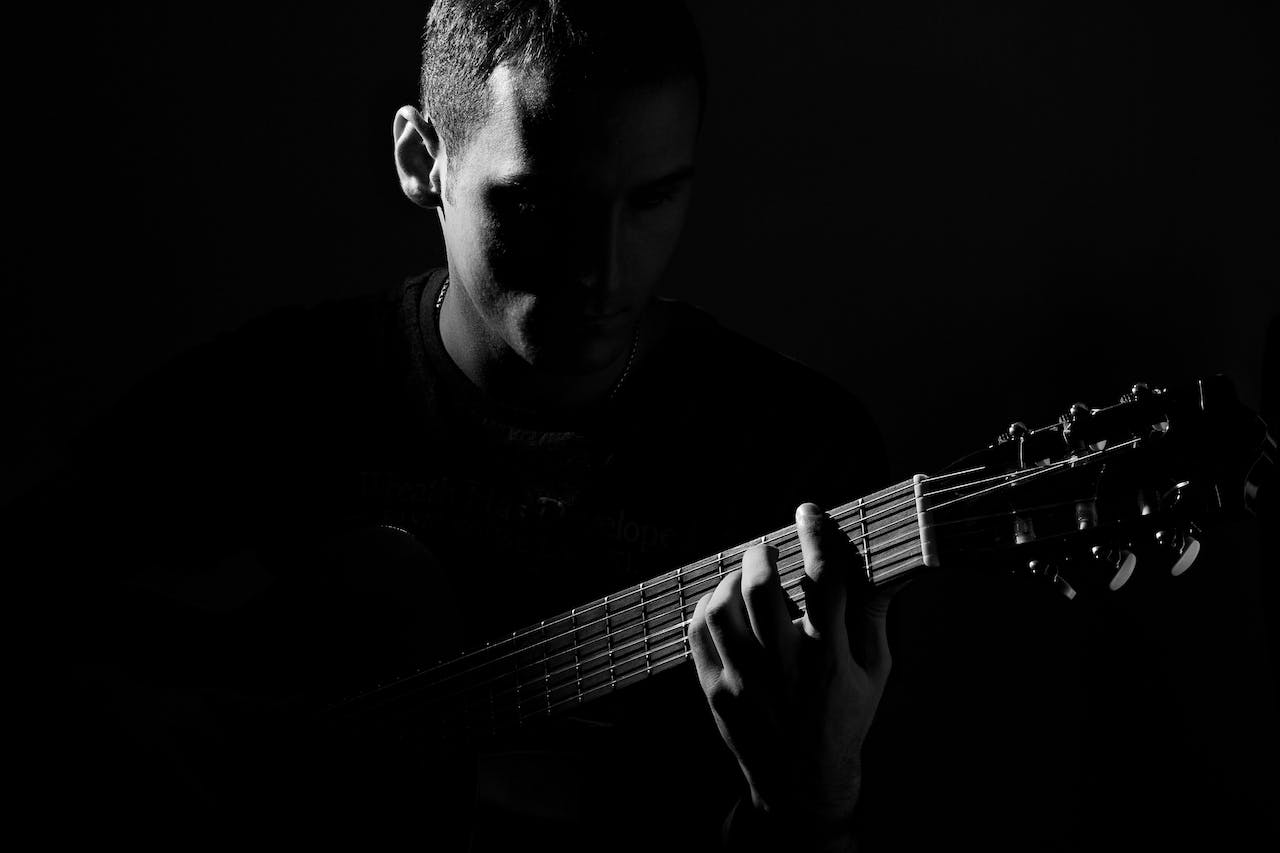 man making music in recovery on guitar in dim light