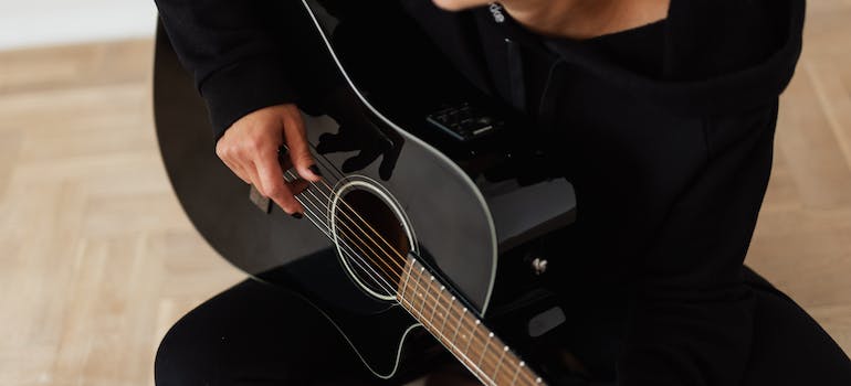 A person playing the guitar as a part of making music in recovery