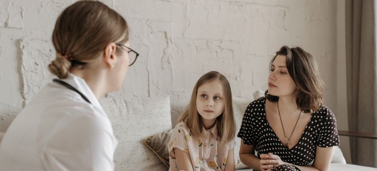Mother and daughter speaking with a doctor during a medical consultation.