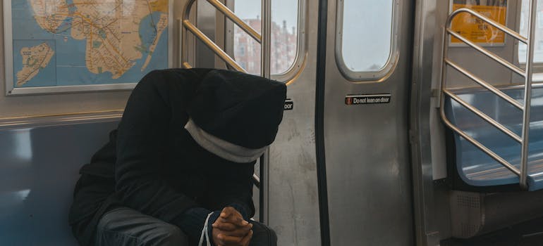 person in a black hoodie riding the subway